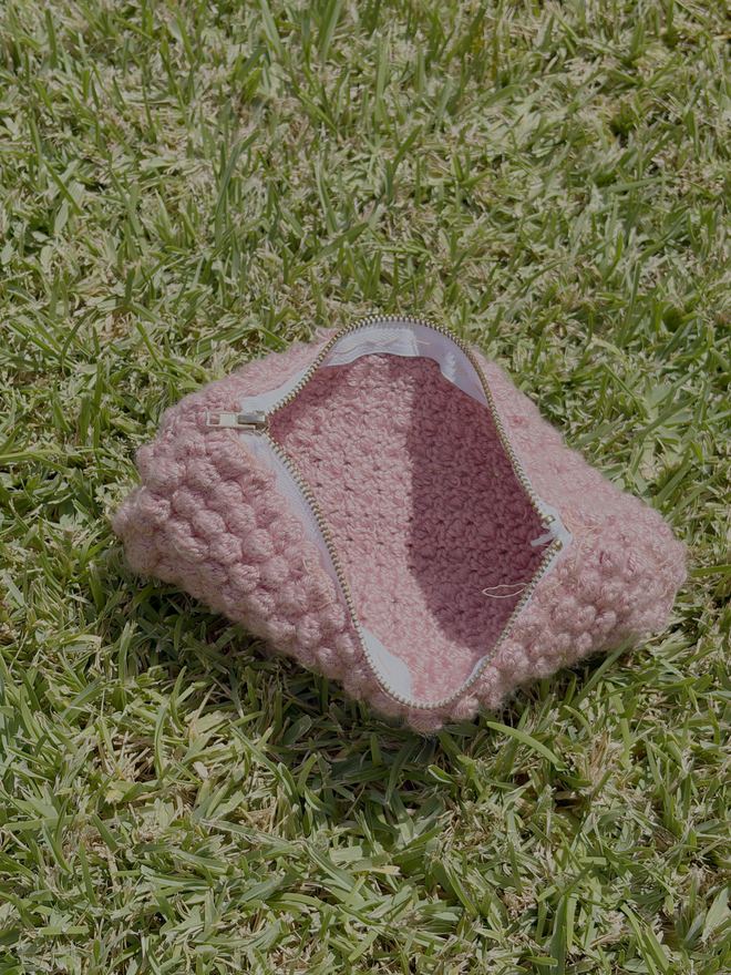 The same pencil case unzipped, showing the crochet lining inside